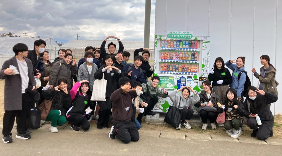 ＜敷地内にあるアサヒ飲料の「CO2を食べる自販機」と笑顔あふれる記念撮影！＞
